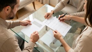 Un couple consulte des documents financiers sobres et une simulation de crédit immobilier sur une table lumineuse, dans une ambiance domestique calme.
