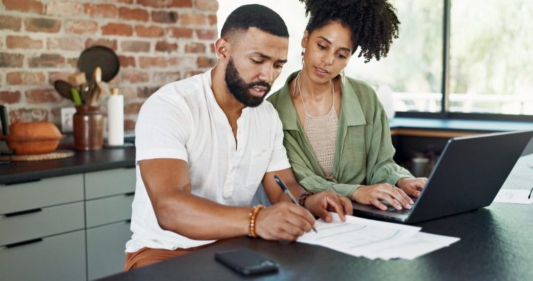 Un couple examine des documents de rachat de prêt autour d’une table.